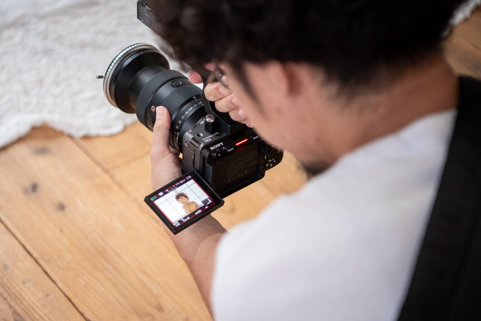 子どもを撮影しているカメラマンの手元とモニターに映る映像