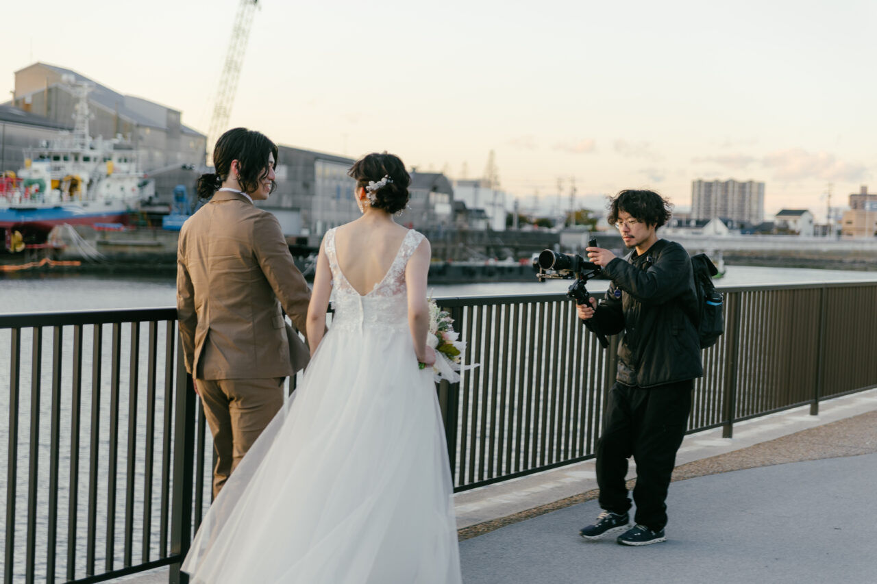 水辺で新郎新婦を撮影する映像クリエイターの様子