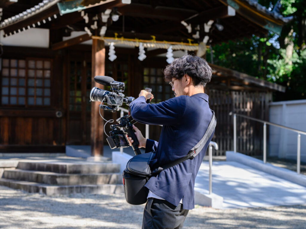 神社境内で映像機材を構えて撮影するクリエイターの姿