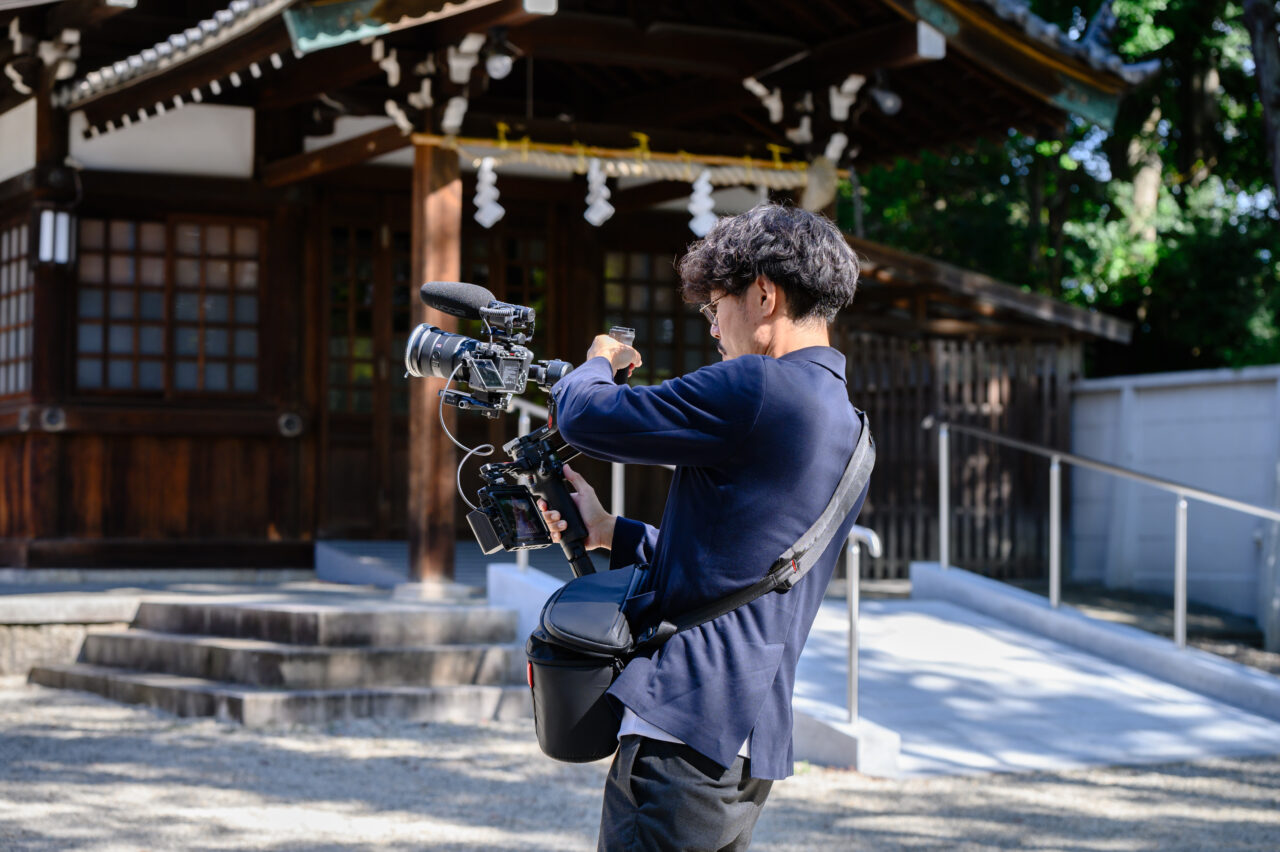 神社境内で映像機材を構えて撮影するクリエイターの姿