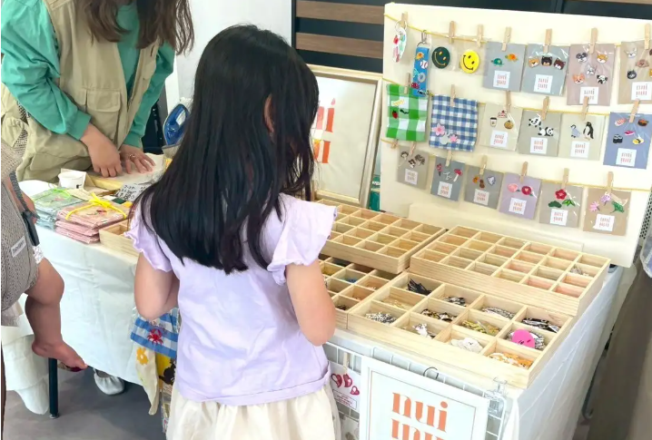 手作りアクセサリーの販売ブースで商品を見つめる子どもの様子