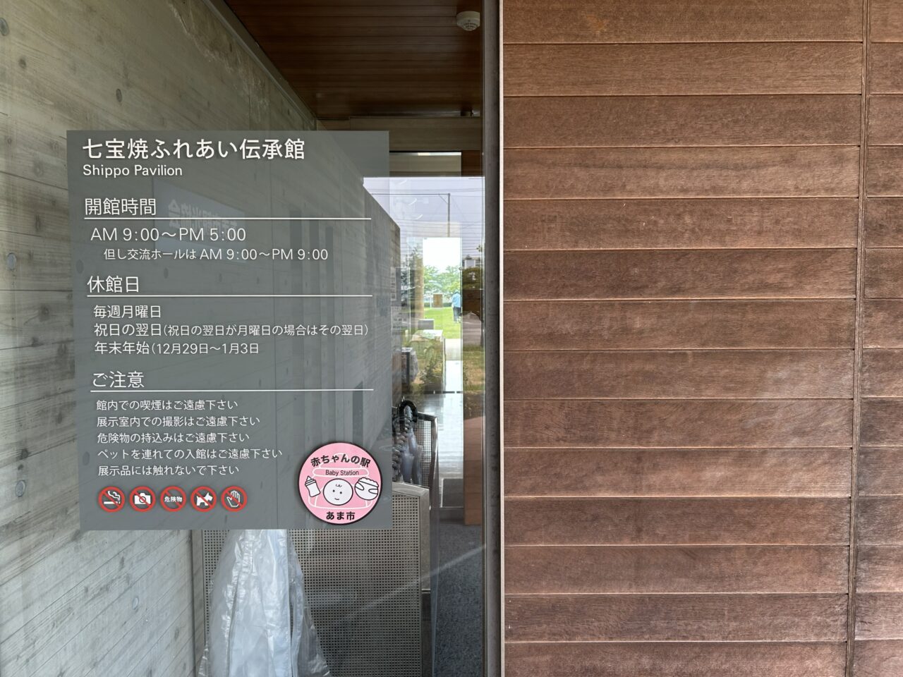 七宝焼ふれあい伝承館の開館情報と注意事項が記載された入口の案内表示