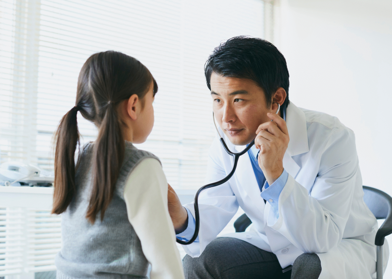 診察室で医師が聴診器を使って子どもの診察をしているイメージ