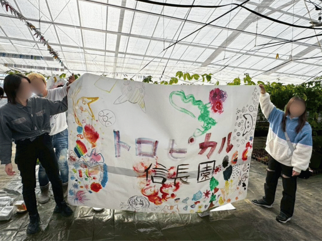 愛西市のトロピカル信長農園で過去に開催されたイベント時の様子。手作りの横断幕を持つ参加者たち