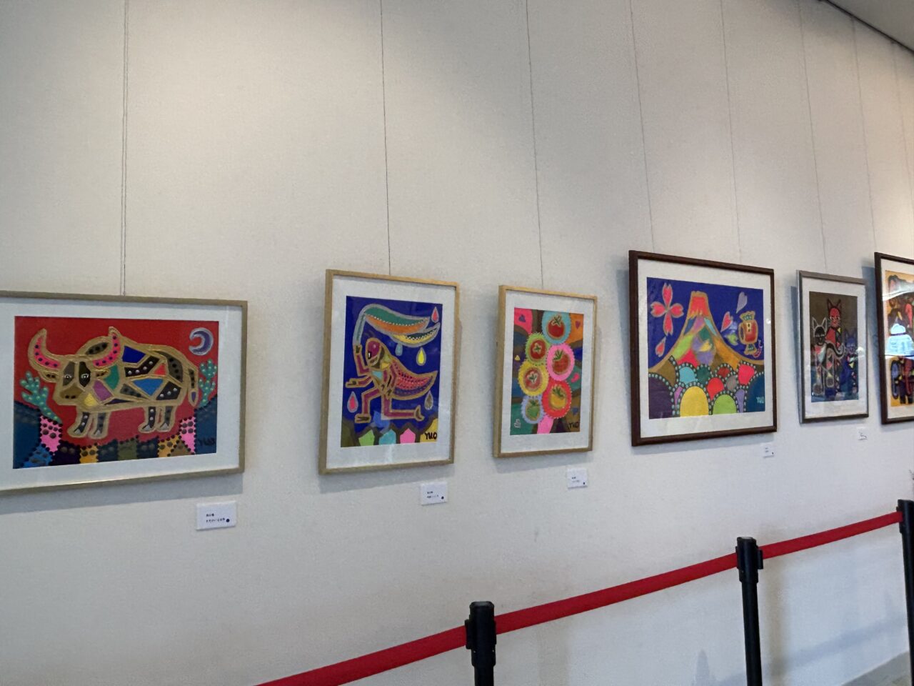 展示会場の壁面に並ぶ奥山優さんのカラフルな動物作品