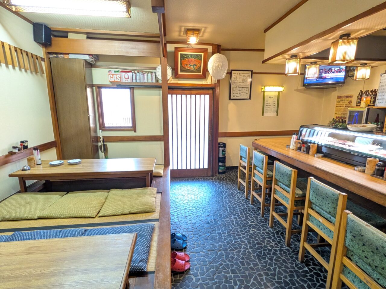 「呑食処 館」の店内全景。カウンター席とネタケース、壁メニューが写る様子