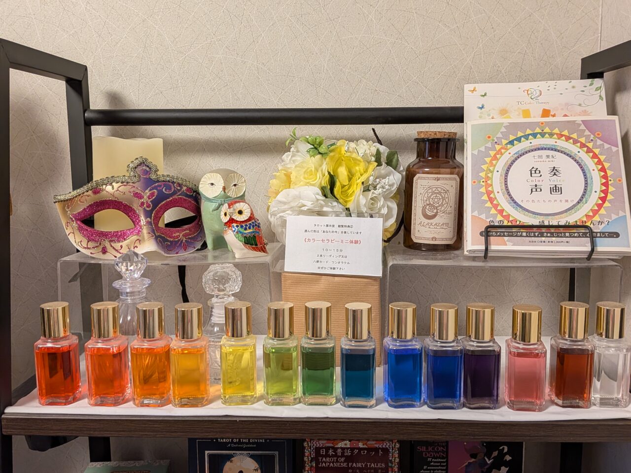 あま市の占いギャラリー「ココロにウルオイ」に並ぶカラーセラピー用の色とりどりのボトルとミニ体験の案内