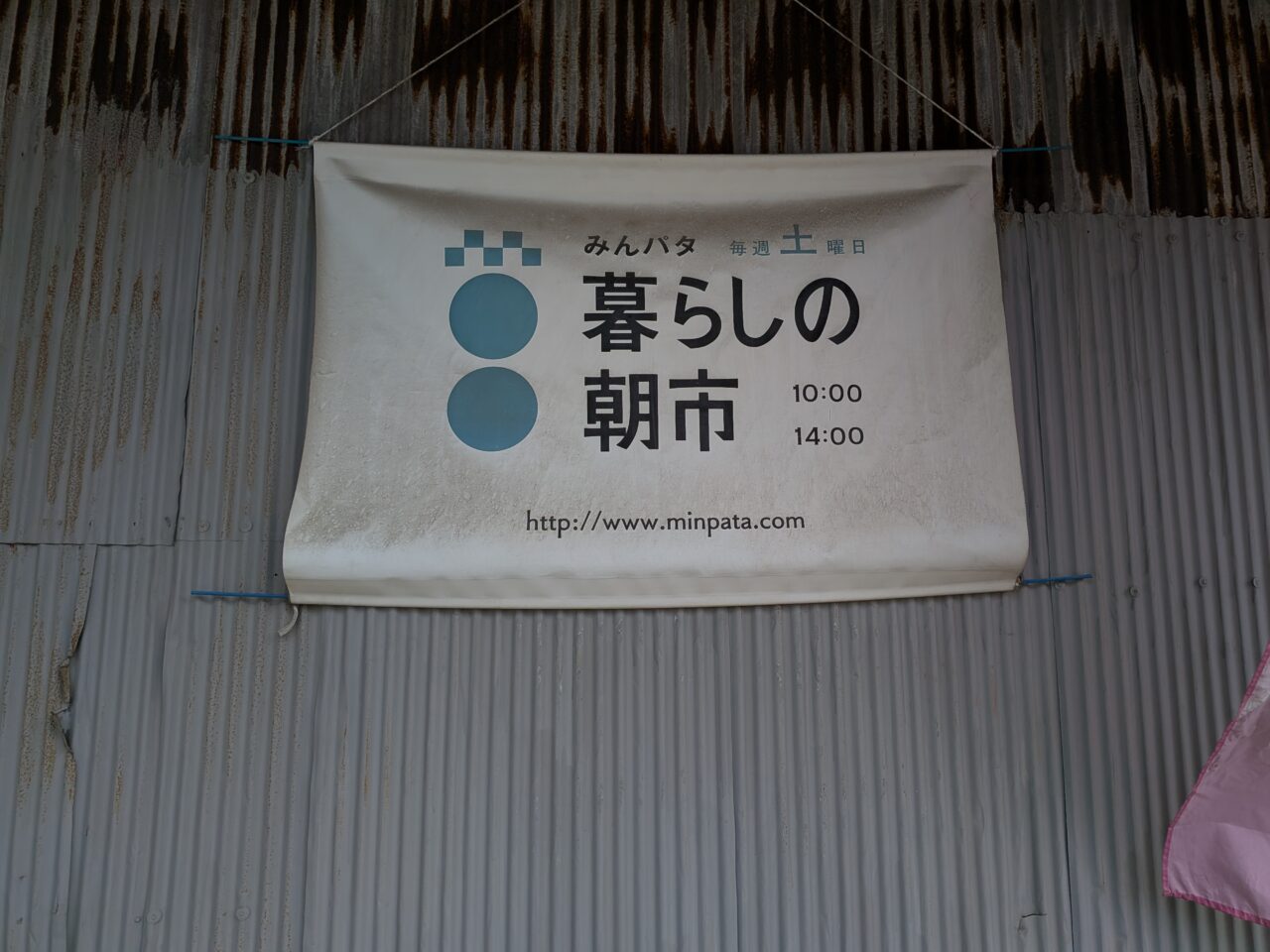 「のこぎり屋根倉庫」に掲示された、毎週土曜日開催「みんパタ暮らしの朝市」のロゴ入り看板。