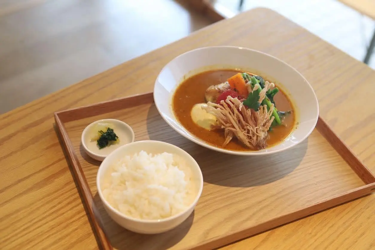 木製トレーに乗せられた食堂αのスープカレーとごはんのセット