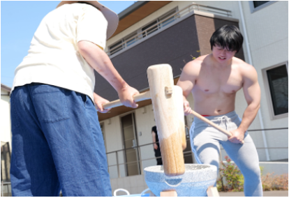 NOIE TSUSHIMAのマッチョ介護士と地域住民が協力してお餅をつく様子