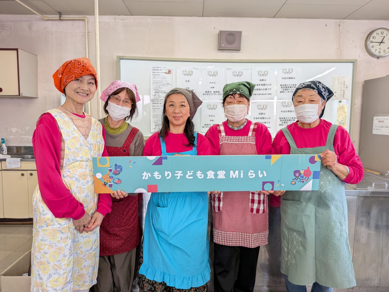 津島市の神守小学校区コミュニティセンター調理室で看板を掲げるかもり子ども食堂Miらいのボランティアスタッフ